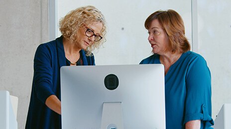 Two women conversing at computer.